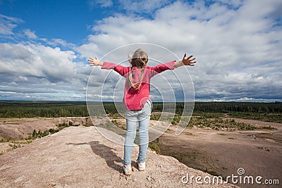 Carefree child girl with hands up against sky clouds outdoors Stock Photo