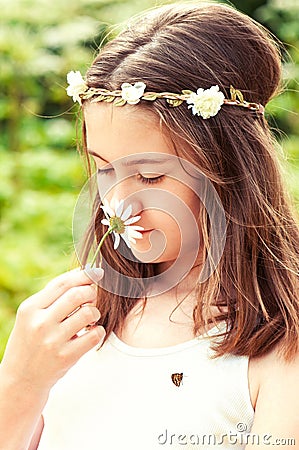 Carefree childhood. Girl with butterfly smelling camomile . Stock Photo