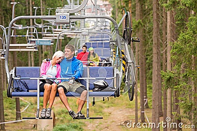 Carefree couple traveling by chair lift wood Stock Photo