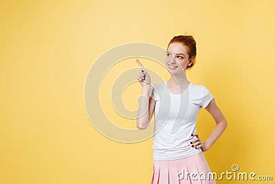 Carefree ginger girl pointing away and holding arm on hip Stock Photo