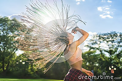 Carefree girl with zizi cornrows dreadlocks dancing on green lawn Stock Photo