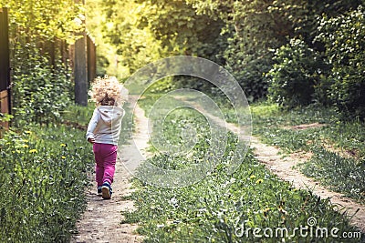 Carefree happy childhood with playful child walking alone on rural footpath in forest during summer holidays Stock Photo