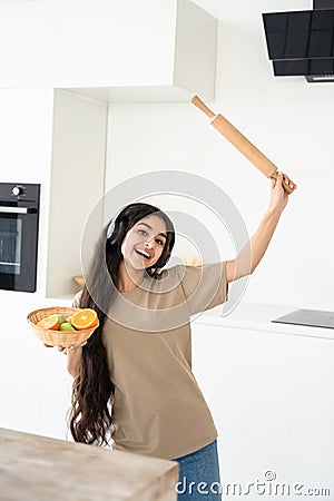 Carefree happy housewife dancing with headphones in modern kitchen, having pleasure cooking, carefree lifestyle Stock Photo