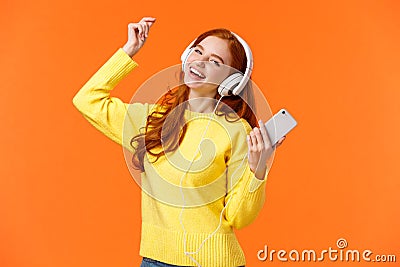 Carefree happy redhead teenage girl receive new headphones for christmas gift, dancing lift hand up while listen Stock Photo