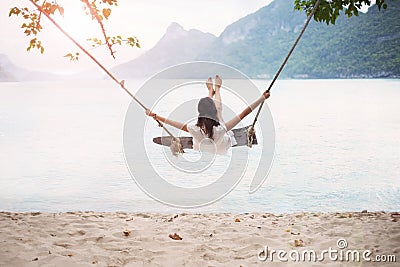 Carefree happy woman on swing on beautiful paradises beach Stock Photo