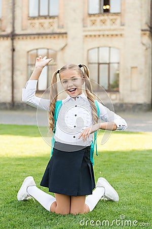 Carefree student. Smiling pupil sit on grass. Have fun. Happy kid relaxing outdoors. Cheerful schoolgirl. Schoolgirl Stock Photo