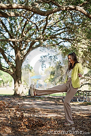 Carefree young woman kicking leaves in the park Stock Photo