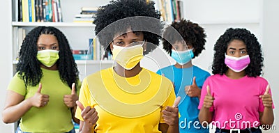 Careful african american woman with yellow face mask and group of female young adults Stock Photo