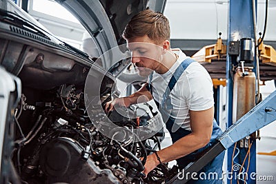 Careful with that. Employee in the blue colored uniform works in the automobile salon Stock Photo