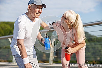 Careful mature woman take care of tired man at training on footbridg Stock Photo