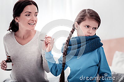 Careful mother with cough syrup and disobeying child Stock Photo