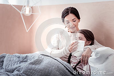 Careful mother lying in the bed with her ill child Stock Photo