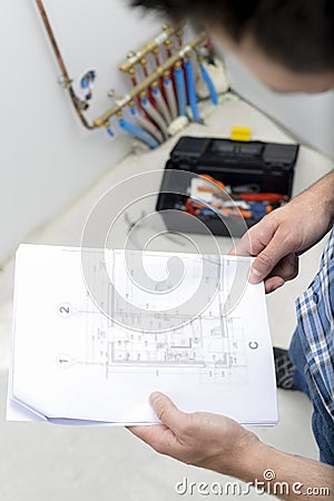 Careful plumber checking plans Stock Photo