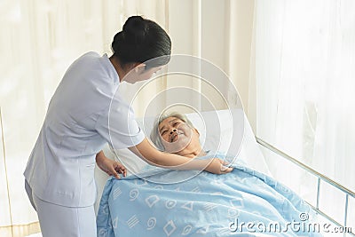 Caregiver in elderly home care giving help grandma on the bed Stock Photo