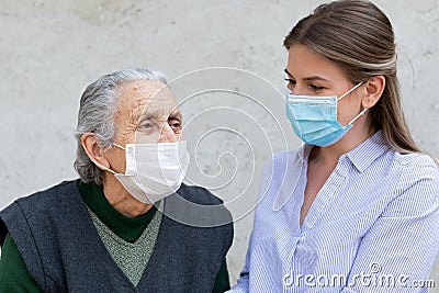 Caregiver with elderly ill woman wearing mask Stock Photo