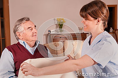 Caregiver gives blanket to happy senior Stock Photo