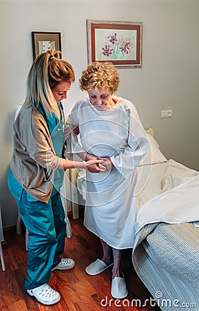 Caregiver helping elderly patient to stand up Stock Photo