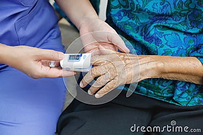 Caregiver monitoring oxygen saturation at fingertip of elderly Stock Photo