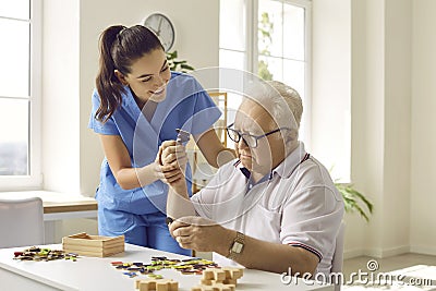 Caregiver or nurse in retirement home helping demented senior patient with games and puzzles Stock Photo