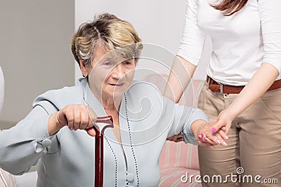 Caregiver supporting senior woman with walking stick Stock Photo