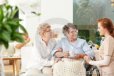 Caregiver talking to a smiling senior woman and her friend in th Stock Photo