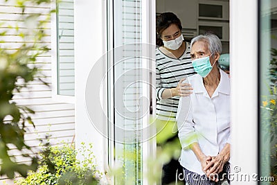 Caregiver woman take care of the elderly,depressed senior is waiting for her family to visit at home,social distancing,nostalgia, Stock Photo