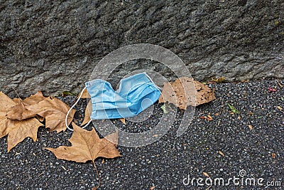 Carelessly discarded blue face mask on a sidewalk during the corona pandemic, Stock Photo