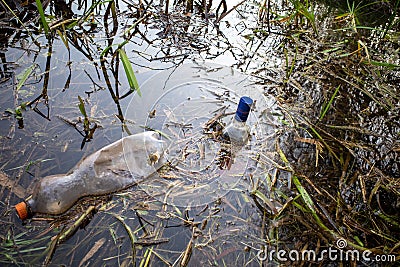 A carelessly discarded plastic bottles and glass liquor bottles float in a lake Stock Photo