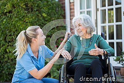 Carer Pushing Senior Woman In Wheelchair Outside Home Stock Photo