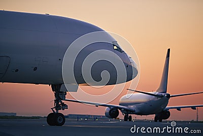 Cargo airplane is taxiing behind passenger airplane at busy airport Stock Photo