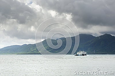 Cargo ferry in tropical sea under monsoon storm heavy clouds and tropical Koh Chang island on horizon in Thailand Editorial Stock Photo