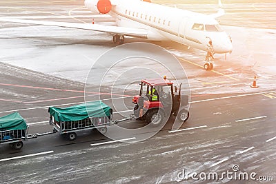 cargo freight tractor machine delivering luggage carts to airplane at airport. Airport carrier and service Stock Photo