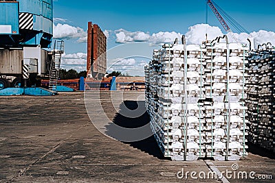 Cargo at the port. Aluminum ingots on the pier. Against the background of cargo depots and ships Stock Photo