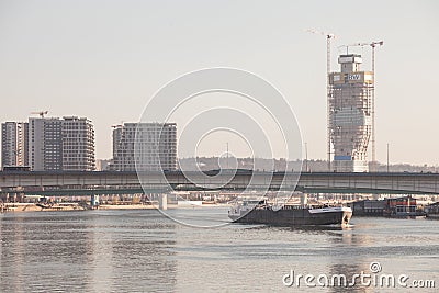 Cargo ship, a barge, under stari savski most bridge on sava river with construction of Belgrade waterfront, or Beograd na vodi. Editorial Stock Photo