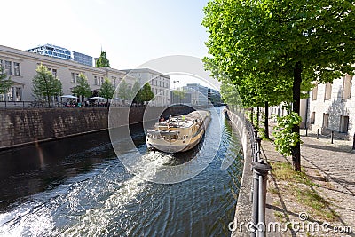 Cargo ship on a river through downtown area of a city, on a sunny spring day- Berlin 2018 Editorial Stock Photo
