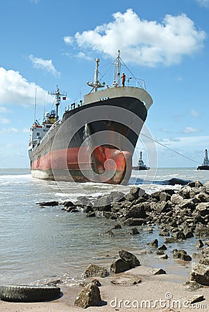 Cargo ship run aground on rocky shore Stock Photo