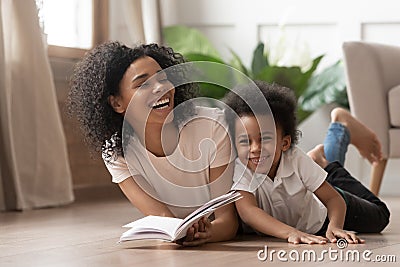 African mom reading book laughing with child son at home Stock Photo