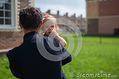 Caring father holds on hands of his little daughter outdoors. Stock Photo