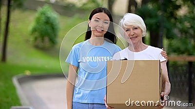 Caring female activist hugging old woman donation card box, social volunteering Stock Photo