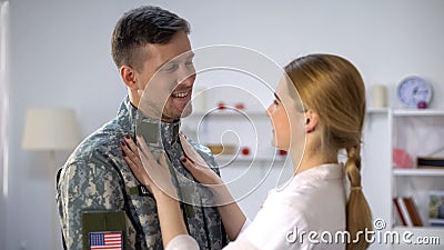 Caring female adjusting uniform of US soldier boyfriend, admiring beloved man Stock Photo