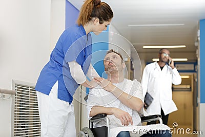 caring female nurse talking to disabled patient in hospital Stock Photo
