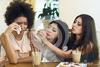Caring friends supporting young crying woman in cafe Stock Photo