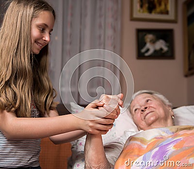Caring girl holding old lady's hands Stock Photo