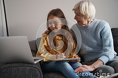 Lovely child and her grandma looking at laptop screen Stock Photo