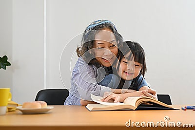 Caring grandma telling story, reading fairy tale to her little granddaughter. Multi generational, family and love Stock Photo