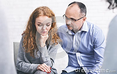 Caring husband supporting his depressed wife at marriage therapy session Stock Photo