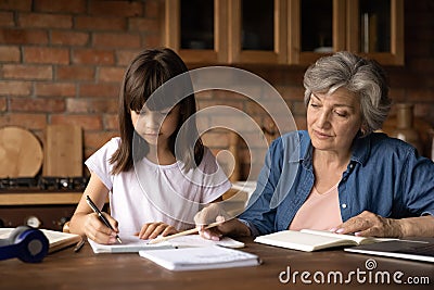 Caring elderly grandmother help little granddaughter with homework Stock Photo