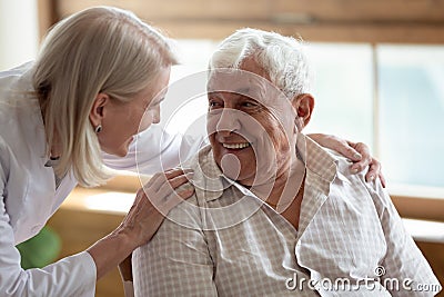 Caring nurse talking to elderly patient 80s man Stock Photo