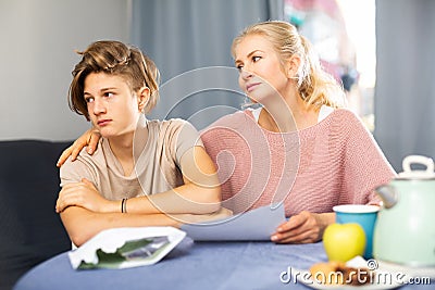 Caring mother calming upset teenage son student receiving test failure notification Stock Photo