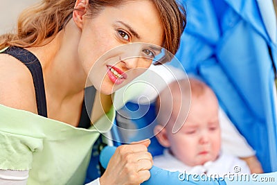 Caring mother hugging sitting in stroller baby Stock Photo